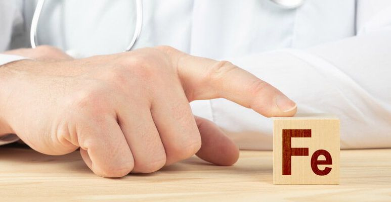 Lekarz dotyka małej drewnianej tabliczki umieszczonej na stole, na której znajduje się symbol żelaza