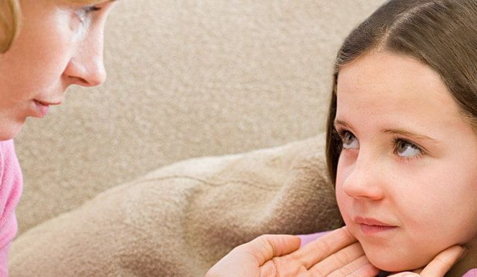 Mama dotyka twarzy córeczki, która wykazuje objawy zakażenia mononukleozą