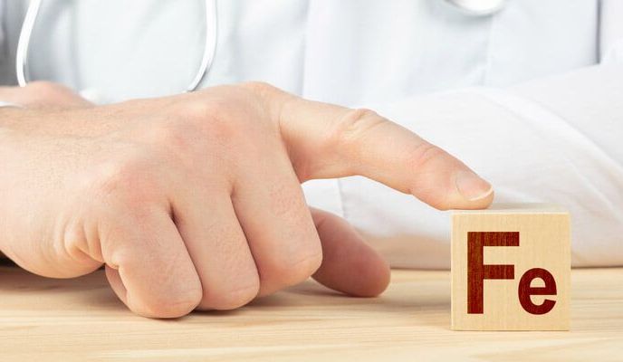 Lekarz dotyka małej drewnianej tabliczki umieszczonej na stole, na której znajduje się symbol żelaza